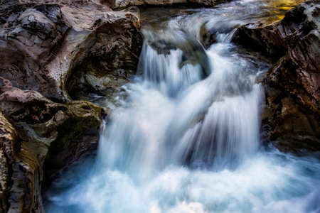 small waterfall of a fast and crystalline mountain river, on a bedrock, long exposure with silk...