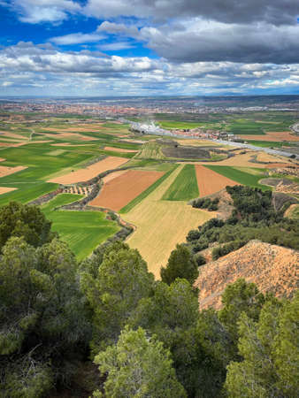 aerial image of the Corredor del Henares with the town of Taracena and cereal fields in the foreground, the city of Guadalajara and in the background the skyline of Madrid on a cloudy day verticalの写真素材