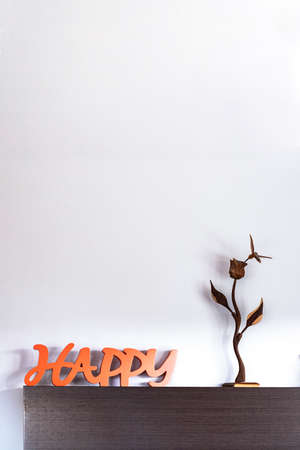 detail of decoration with the message of happy, a wooden flower with a hummingbird feeding, orange tones on wenge wood, copy space, verticalの写真素材