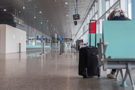 a female traveler sits on her back in a lonely airport terminal with her trolley in the foreground,...