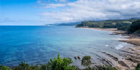 panoramic view of the Asturian coast viewed from Lastres, with white sandy beaches mixed with green mountains and a blue sky with cloudsの写真素材