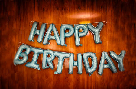 happy birthday message made with metallic blue balloons on a cherry wood background, horizontalの写真素材