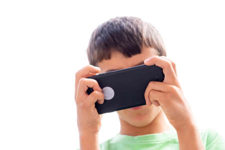 a child playing with a smart phone with her face covered by the cell phone, hands in the foreground with selective focus, horizontalの写真素材