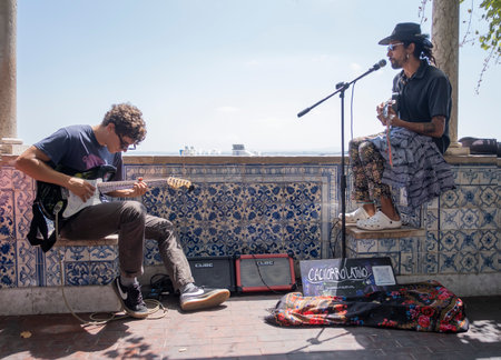 two street musicians play guitar for tourists at the mirador de santa lucia, in the Alfama district...