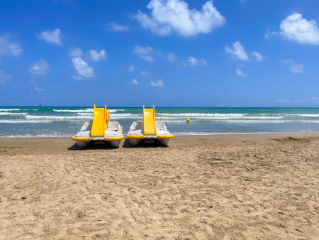 pedal boats hire, an empty beach on a summer day with 2 yellow paddleboats with slide on the seashore, rental paddle boats on the beach, horizontalの写真素材