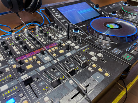 dj mixer, with numerous knobs and dials with various displays and colored lights, electronic music,...