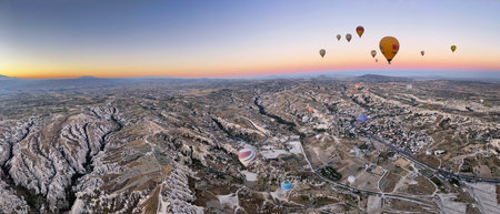 panoramic view of a goup of hot air balloons flying over the fairy chimneys, at the Goreme airfield at dawn, Cappadocia, Turkey, copy spaceの写真素材
