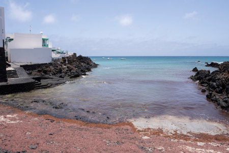 small cove on a volcanic coast with white houses of fishermen, red seaweed on the shore and turquoise waters in the background, Punta Mujeres, Lanzaroteの写真素材