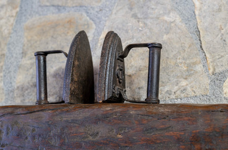 Two antique iron plates on a wooden shelf on a stone background, in an antique and rural environment, selective focusの写真素材