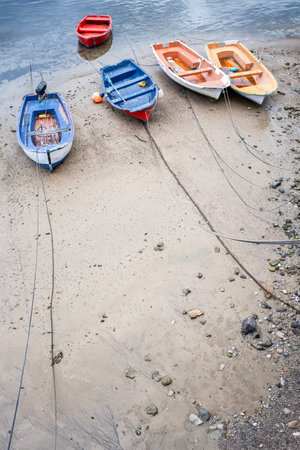 five colorful small boats moored on the shore of a beach with their ropes sticking out of the image, copy spaceの写真素材