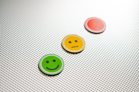 Three round emoji faces in red, yellow, and green representing sad, neutral, and happy emotions on a metallic textured background, symbolizing feedback or mood scaleの写真素材