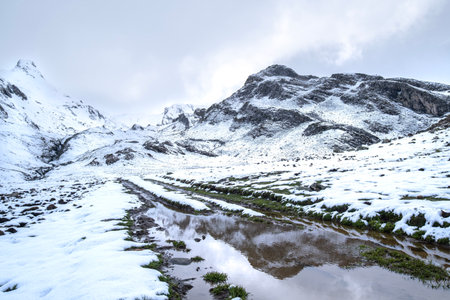 an image of the early spring thaw with a large puddle in the foreground reflecting the snow-capped mountaintop in the backgroundの写真素材