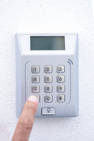 Close-up of ahand pressing a button on a numeric keypad for a security system or entry doo, the...