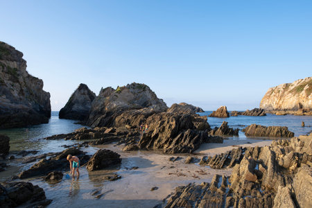 Asturias, Spain; August 20 2025: Group of children playing with fishing nets among the rocks at Porcia Beach in Asturias Spain during sunset The scene captures summer fun, friendship, and natureのeditorial素材