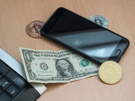 Two bitcoins, along with a dollar, a mobile and a keyboard. Business issuesの写真素材