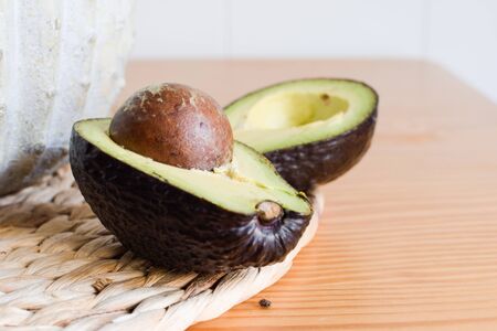 Avocado cut in two on a wooden table and unfocused background