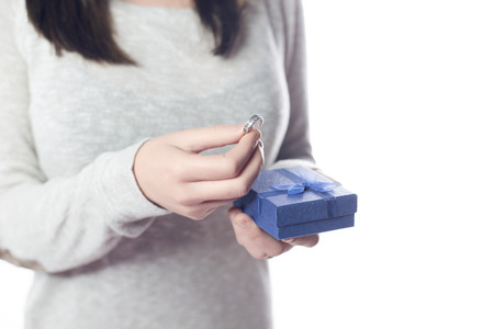 Hands with a ring and a gift box, isolated on a white background.の写真素材