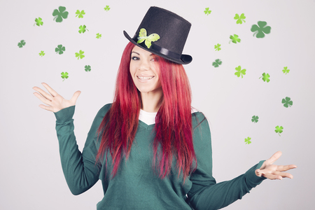 Happy woman celebrating Saint Patrick's day on march 17th, smiling surrounded by shamrocks and clovers.の写真素材