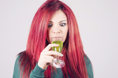 Happy woman celebrating Saint Patrick's day on march 17th, looking astonished to a glass of green beer.の写真素材
