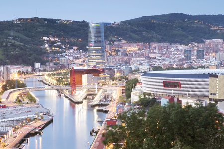 Bilbao, Basque Country, Spain - May 24, 2016: View of the illuminated city of Bilbao in the sunset, with Nervion river, San Mames football stadium, Iberdrola tower, the Ria de Bilbao Maritime Museum, or the Euskalduna Conference Center.のeditorial素材