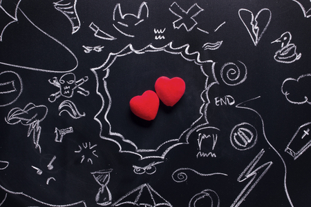 Two hearts surrounded by troubles and problems. Love will find a way! Hand drawing on a black board.の写真素材