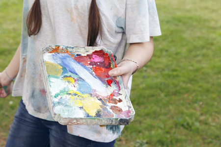 Young brunette woman artist, painting in canvas. Outdoors, in nature.の写真素材