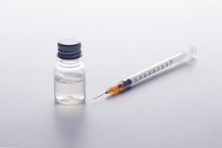 Substance abuse!. One syringe and a mysterious vial on a white table. Self-medication. Health danger.の写真素材