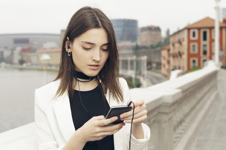 Young woman using her smart phone on the street, outdoors in the city.の写真素材