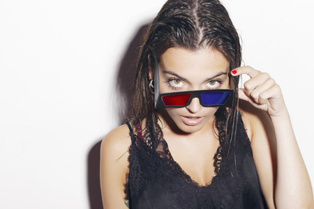 Brunette girl with retro 3d glasses, indoors, over a white background.の写真素材