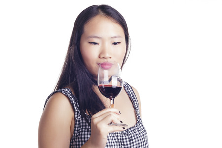 Asian girl with a glass of red wine, over a white background, isolated.の写真素材