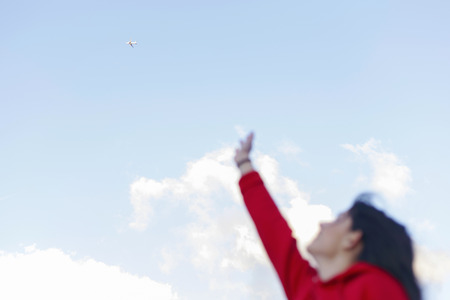 Blurred silhouette of a young woman, trying to touch a airplane in the sky. Dreams and hope.の写真素材