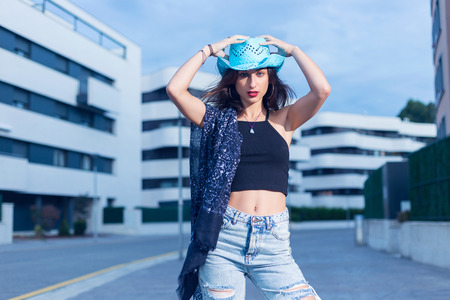Young beautiful brunette woman wearing a blue hat, standing in a empty street. Street fashion.の写真素材