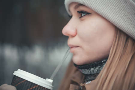 A young blonde girl drinks a drink through a straw. close up photo.の写真素材