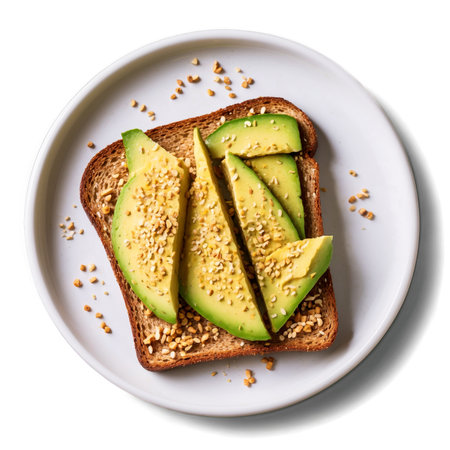 A highangle shot showcases avocado toast on a white plate, topped with sliced avocado and sprinkled nuts. Perfect healthy breakfast or brunch option.の素材
