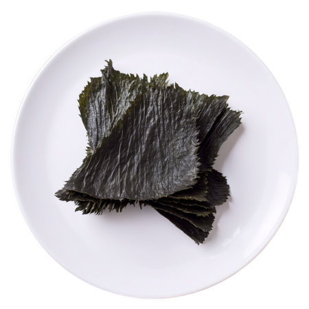 This image shows a stack of dried seaweed leaves on a white plate, ready to be enjoyed as a snack or used in Asian cooking. It highlights the textures and colors of the seaweed.の素材