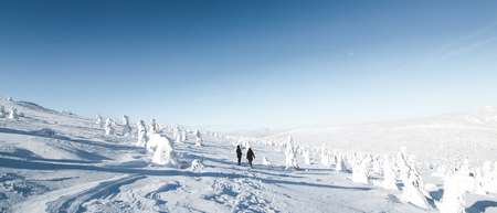White beautiful winter landscape with mountains, blue sky and trees covered with fresh snow with people.の写真素材