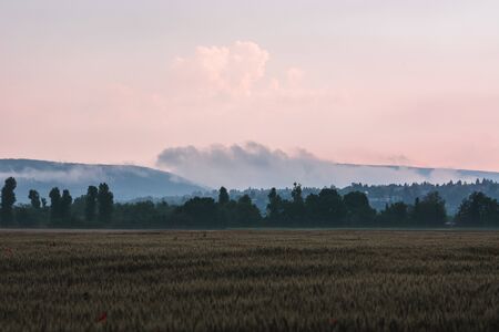 Late evening light and moody clouds with fields in Czech republicの写真素材