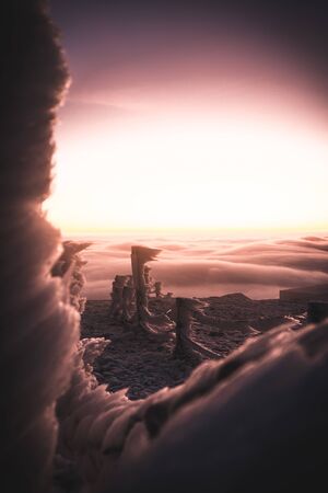 Winter landscape in Krkonose, beautiful sunrise with fence and big moon shot from highest mountain in Czech republic called Snezka.の写真素材