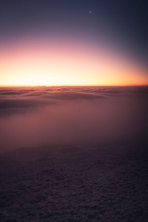 Winter landscape in Krkonose, beautiful sunrise with moon above the heavy clouds, shot from highest mountain in Czech republic called Snezka.の写真素材
