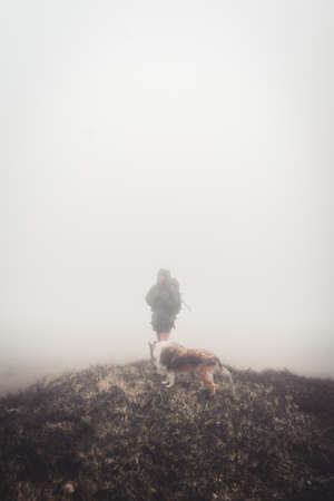 Woman standing with the dog on plains covered in thic fogの写真素材