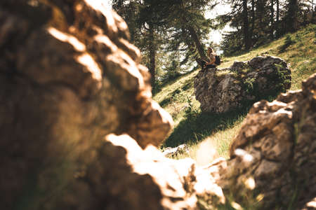 Young woman sitting on rock outdoors watching a beautiful landscape of Triglav national park mountainsの写真素材