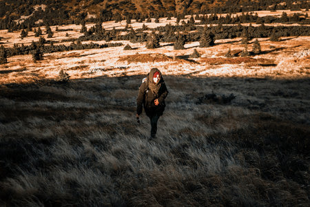 Happy woman enjoying the nature, walking in shadow of big hill, calm, sunset over mountain peaks in...