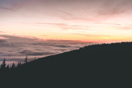 Sunset view in the Krkonose Mountains during autumn. Landscape above clouds. Purple pink sky with sun going down. Czech Republic.の写真素材