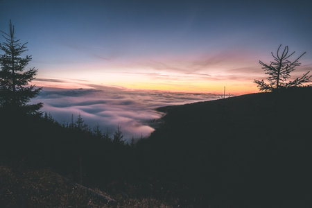 Sunset view in the Krkonose Mountains during autumn. Landscape above clouds. Purple pink sky with sun going down. Czech Republic.の写真素材