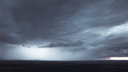 Big dark storm with sunbeams coming through them in the background. On the right side is a clear sky with sunset. Dark clouds rainの写真素材
