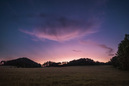 Evening meadow with interesting clouds on purple sky, Hrensko, Czech republicの写真素材