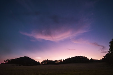 Evening meadow with interesting clouds on purple sky, Hrensko, Czech republicの写真素材
