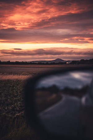 A beautiful sunset is captured and reflected in the rear view mirror of a moving car, creating a stunning visual experienceの写真素材