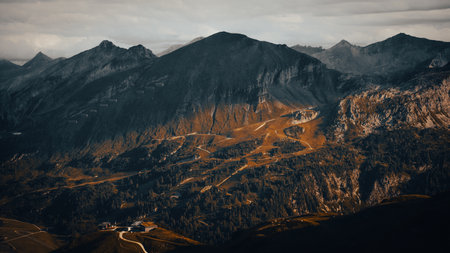 A beautiful mountain, lushly covered in trees, stands majestically with a winding road that gracefully goes through its picturesque landscapeの写真素材