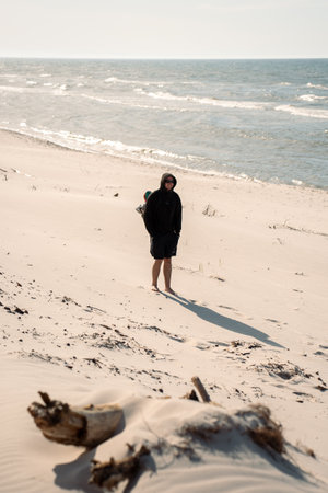 A solitary individual is standing on a vast sandy beach that is located right next to the beautiful ocean.の写真素材